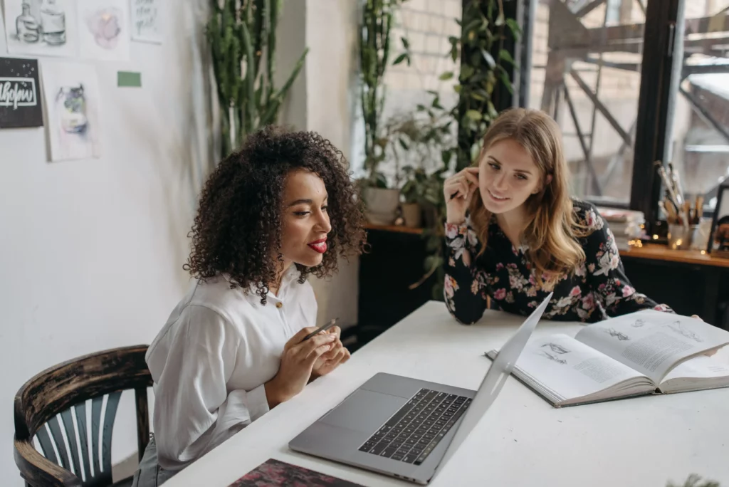 Two women working together at a laptop during a business training and mentoring session